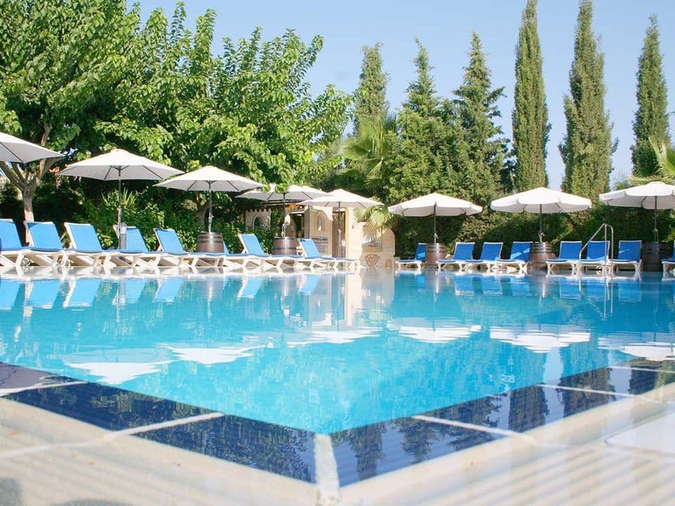 A stunning view of the pool and gardens, featuring sunbeds for every guest and a dedicated area for relaxation and comfort.