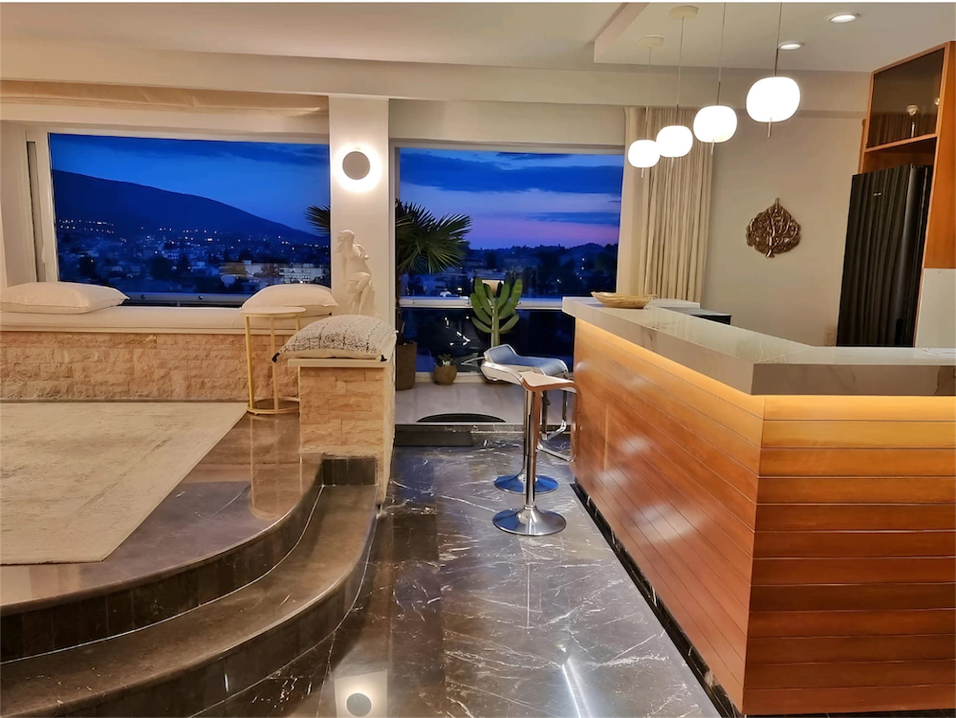 Another view of the elegant indoor living space and the Sky-Bar, showcasing the sophisticated décor and expansive windows that frame the city lights at night