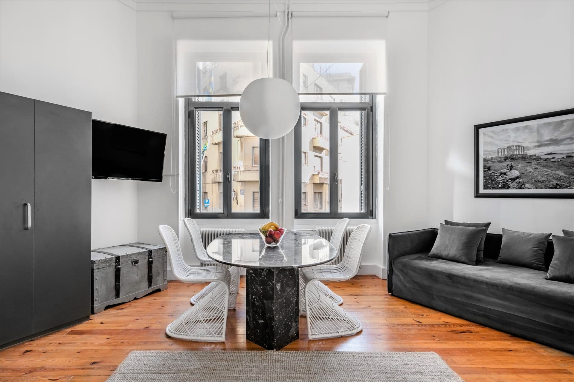 Living room with vintage marble dining table at center, kitchenette on the left and sofa-bed on the right