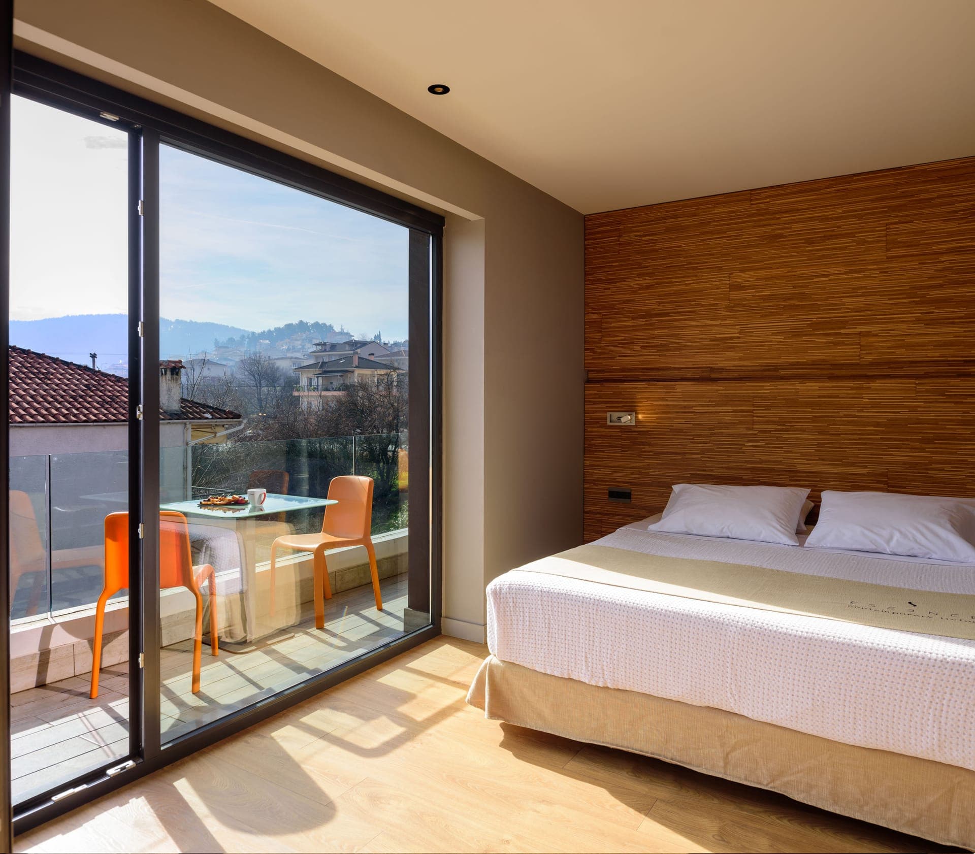Spacious bedroom with comfortable double bed and private veranda or balcony with pool view